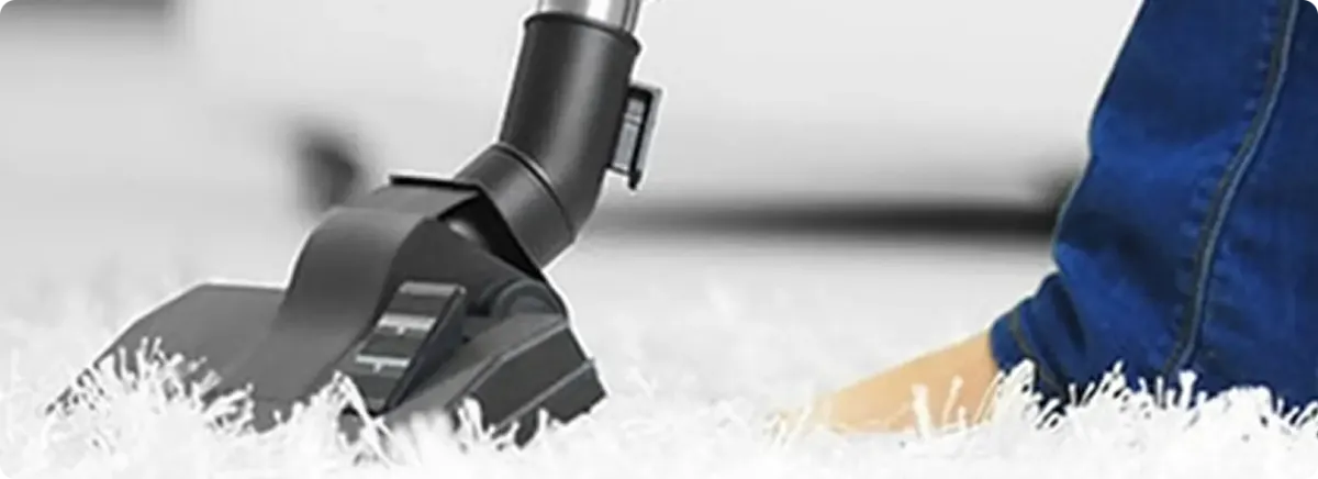 Close-up of a professional vacuuming a white carpet in Opa Locka.